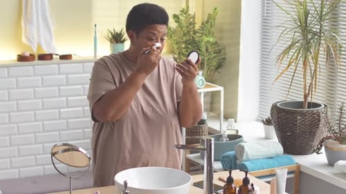 Woman Applies Makeup in Bright Bathroom