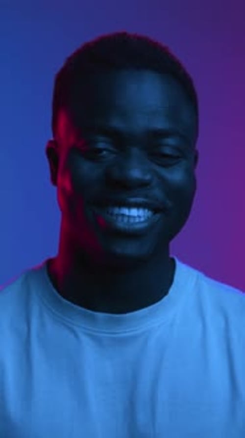 Happy Portrait of Black Man Face Looking at Camera and Smiling in Neon Studio