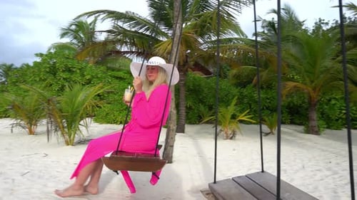 Woman Relaxing on Swing at Tropical Beach
