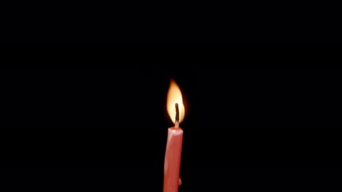 A red candle on a black background rotates, blows the wind and blows it out.