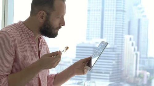 Man Reading News on Tablet During Breakfast Sitting on Bed at Apartment Adult