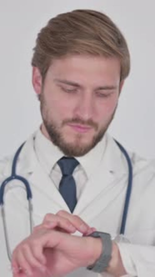 Young Doctor Using Smartwatch on White Background, Vertical Video