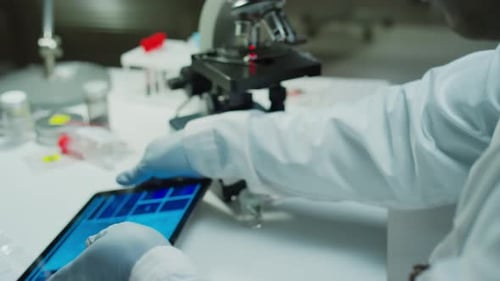 Forensic Scientist Examining Evidence and Microscopic Image on Digital Tablet