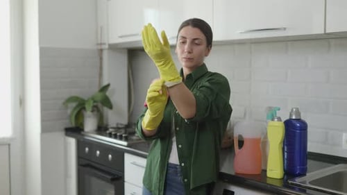 Authentic Young Woman Putting on Yellow Gloves for Household Chores