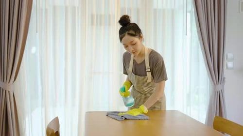 Woman Cleaning Table at Home with Spray Bottle