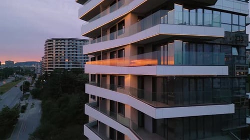 Modern Residential Building with Glass Balconies and LED Lighting at Sunset Urban Architecture and