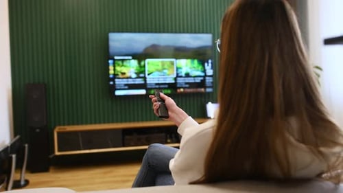 Woman Watching TV with Remote Control on Sofa