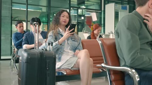 Happy Asian young beautiful woman curly hair taking selfie by smartphone at airport terminal hall