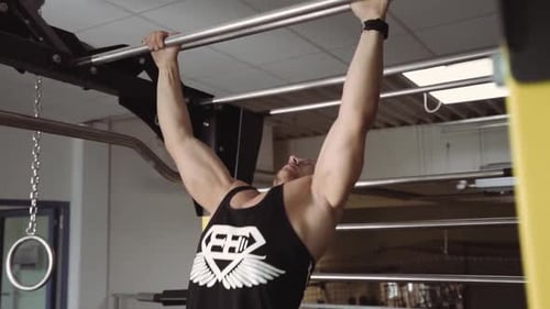 Young blonde caucasian man performing Pull Up on bar in gym workout