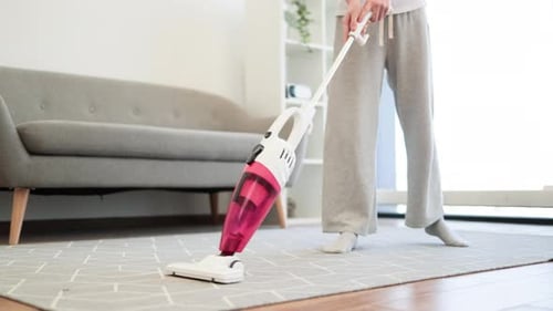 Adult vacuuming rug inside a modern home