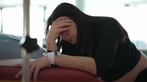 Schwangere Frau leidet an Kontraktionen während der Vorgeburt in der Krankenhausklinik und bedeckt Gesicht, als sie