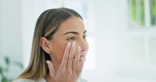 Young Woman Applying Face Cream in Bathroom