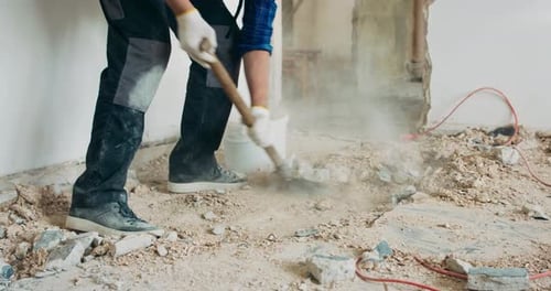 Busy Builder Collecting Construction Debris with a Shovel