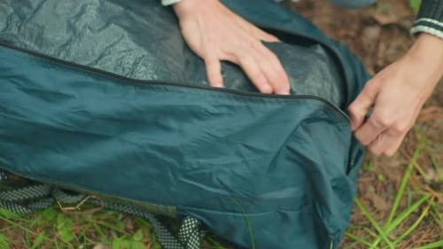 Top Down View of Person Adjusting Tent Bag While Zipping Green Outdoor Gear Bag