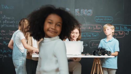 Girl smiling and looking at camera while friend working at board. Erudition.