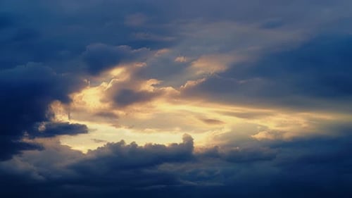 Dark storm clouds with breaking sun rays in the evening sunset sky, time lapse. Dramatic sky with te