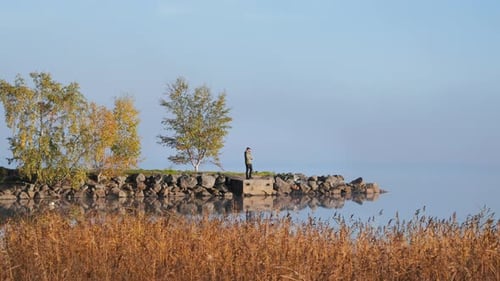 Peaceful calm lake atmosphere with still water, person enjoying scenery, wide