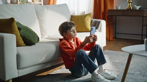 Boy Sits On Floor Using Mobile Phone