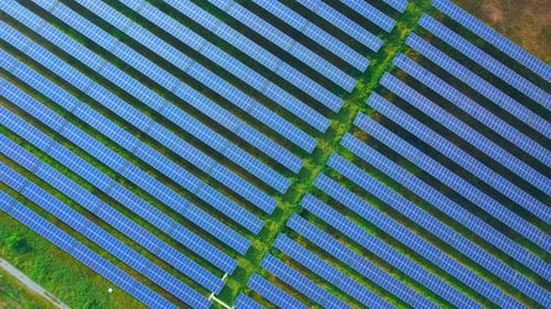 Aerial View of Blue Solar Panels in Green Field