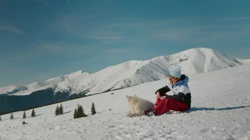 Caucasian Woman with dog having rest after walking on peacky mountains.