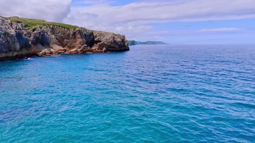 Footage above the blue waterscape at the cliff rocks on the shore.
