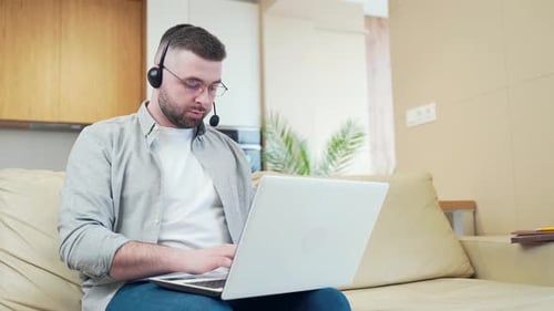 Man Using Laptop and Headset While Working at Home