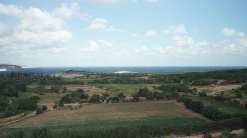 AERIAL: Revealing Part of Comino Island and Farmlands with Village in Background