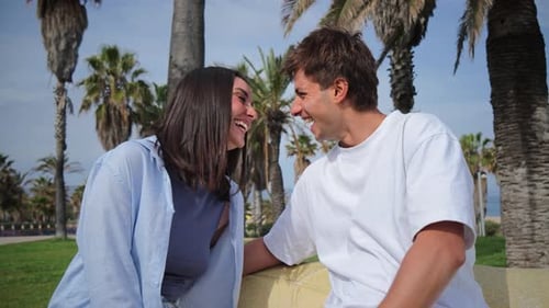 Joyful Couple Sharing Laughter and Intimate Moments While Sitting Close in a Sunny Outdoor Park