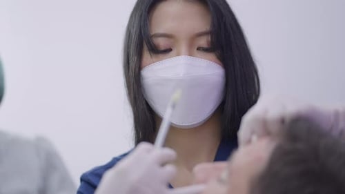 Young Focused Doctor Applying Beauty Injection on Patients Forehead