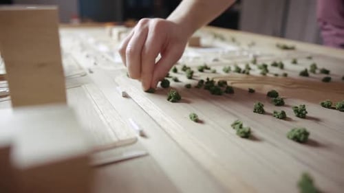 Una persona decora una miniatura artificial con plantas