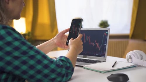 Woman doing financial trading on the phone. Graphic analysis.