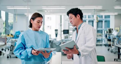 Doctors Reviewing Data on Tablets in Hospital Room