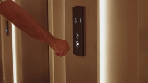 Mann drückt Aufzugsknopf im Innenraum
