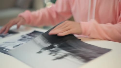 Man in Pink Hoodie Choosing Black and White Pictures for Exhibition