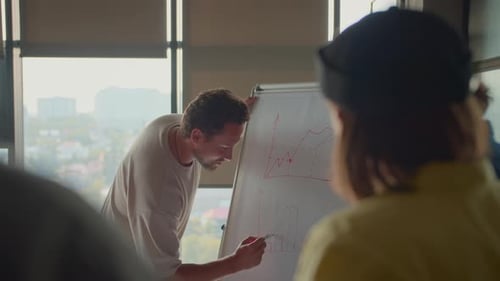 Man Team Leader Shows Data Diagrams Drawn on Whiteboard
