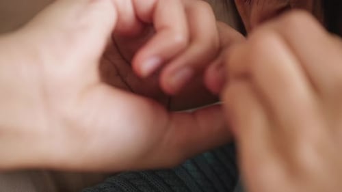 Fingers fiddling with earring and struggling to put it in. Static close-up.