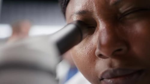 Imagem aproximada do cientista colocando amostra de bandeja sob microscópio no laboratório de química