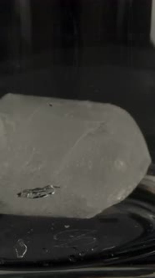 Vertical of Ice Falling Into Glass Cup