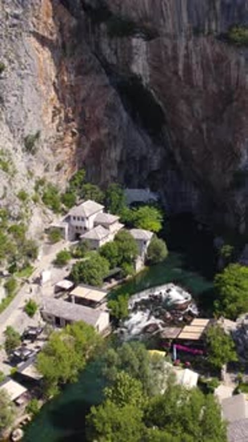 Revelação aérea do Mosteiro Blagaj Tekija e do Rio Buna junto a um penhasco na Bósnia