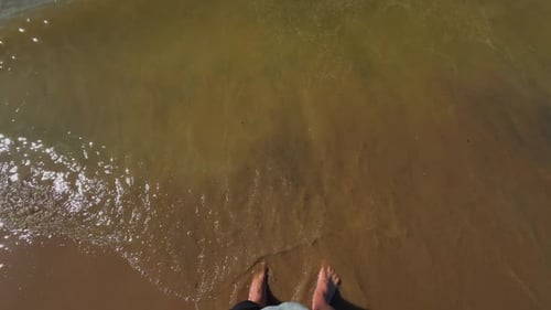 Footsteps on the Shore Enjoying Calm Ocean Waves and a Sandy Beach Under the Bright Sunlight and