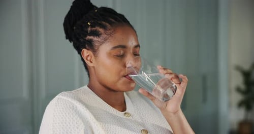 Glass, drinking water and smile with black woman in kitchen of home for detox drinks
