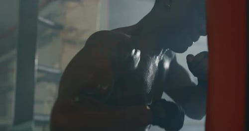 Cinematic shot of a professional young muscular shirtless african man is practicing shadow boxing