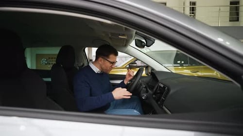 Excited Man Sitting in New Car at Dealership