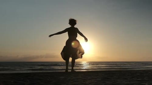 Silhouette Woman Dancing on Beach at Sunset