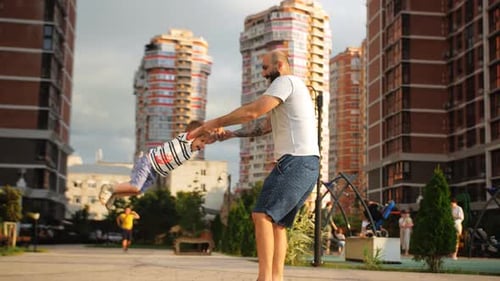 Un père heureux tourne autour de lui en tenant les mains de son petit fils sur fond d'un