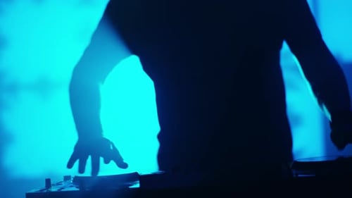 DJ rétroéclairé jouant de la musique dans une boîte de nuit. Silhouette d'un DJ