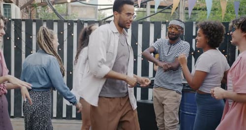 Slow Motion of Excited Young Men and Women Dancing Outdoors in Street Bar Listening to DJ Music and