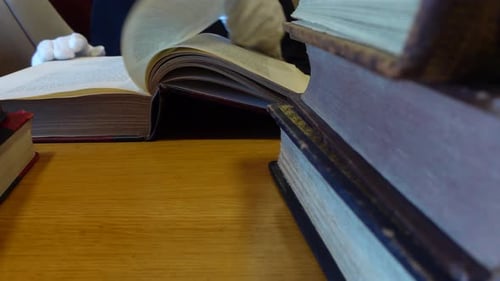 Man's hands leafing through an old book in the library