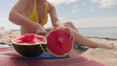 Une femme en pique-nique sur la plage de la mer coupe une pastèque