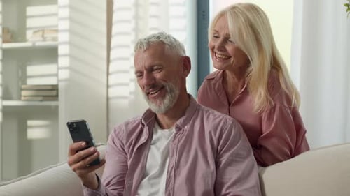 Mature Couple Using Smartphone on Sofa Together